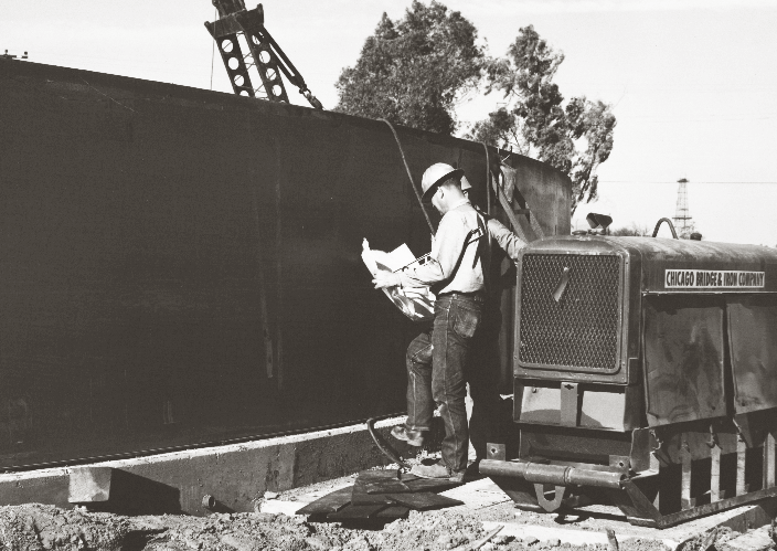 Construction worker at a black steel water tank wall during Cal Water expansion